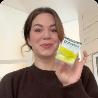 Person holding a Dulcolax product package, smiling.